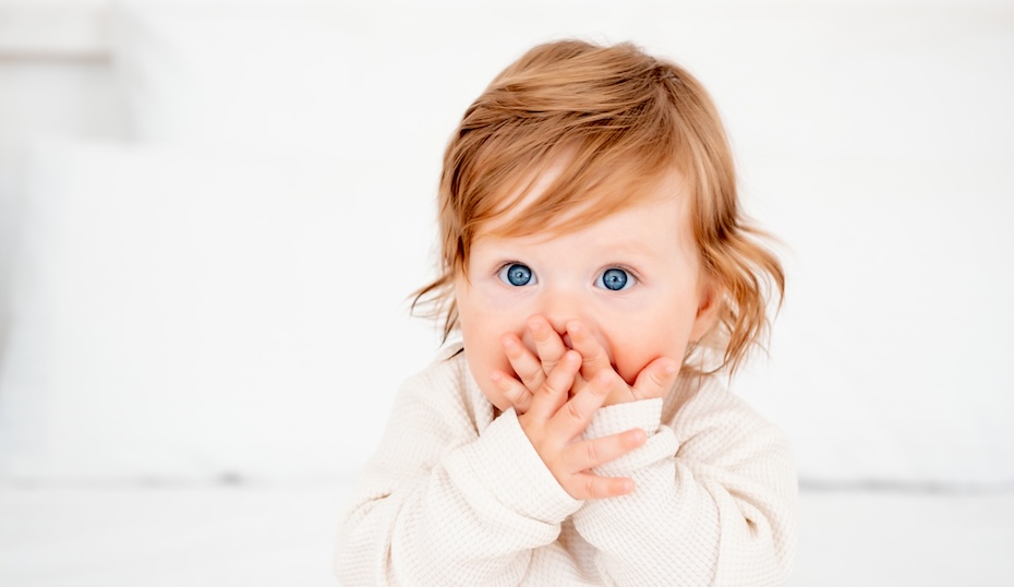 Portrait of a surprised baby with red hair and blue eyes