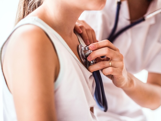 pediatrician using stethoscope on female patient